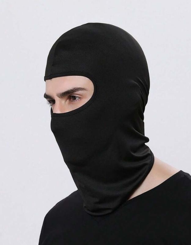 A person wearing a black full face mask covering the head and neck, suitable for cold-proof and wind-proof cycling.